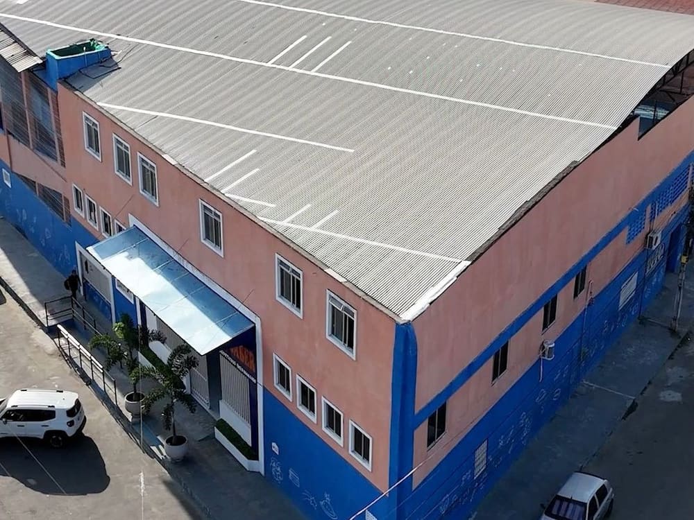 Vista aérea do prédio do Colégio Universo do Saber, azul e salmão, na esquina