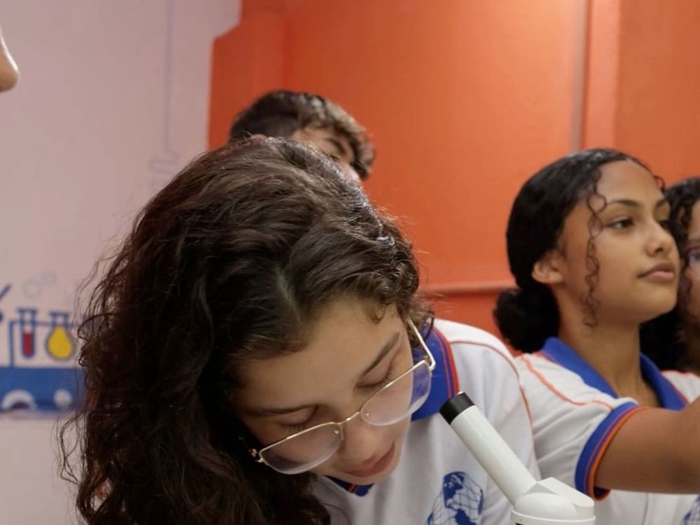 Alunas olhando no microscópio durante a aula de ciências