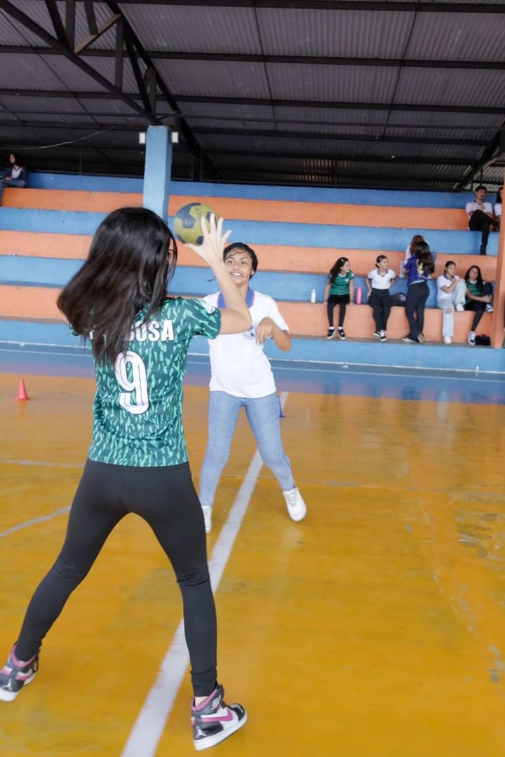 Aluna com a bola de futsal na quadra, de costas, com a camisa 9