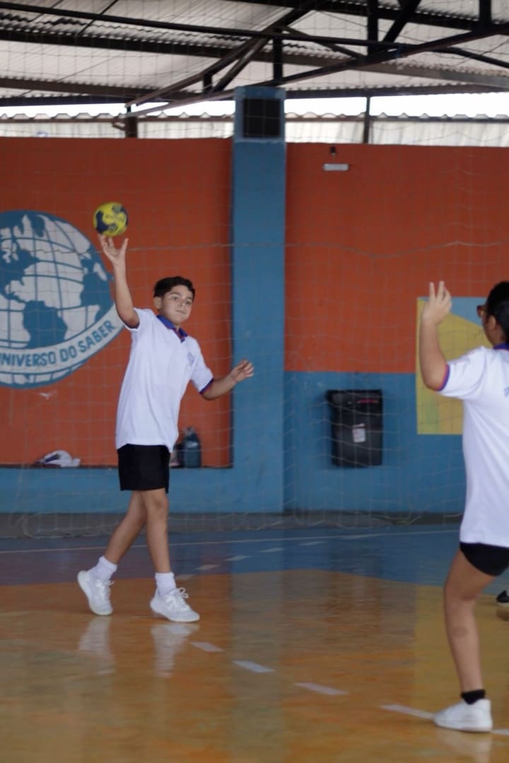 Aluna saltando para alcançar a bola na quadra