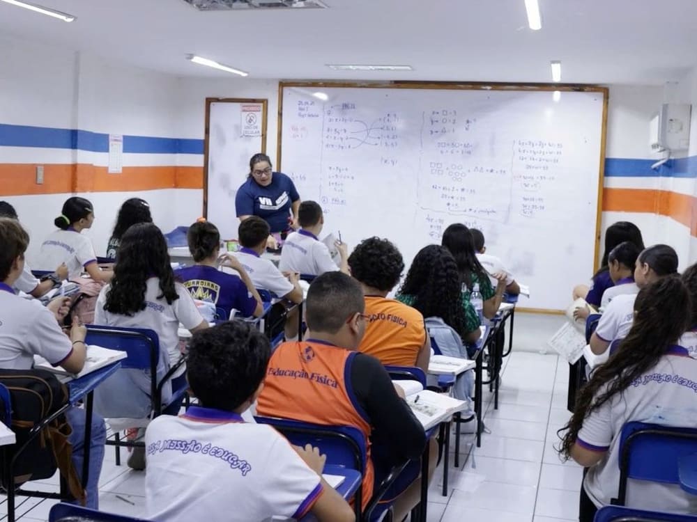 Sala de aula do Fundamental II, com os alunos nas carteiras e a professora no quadro